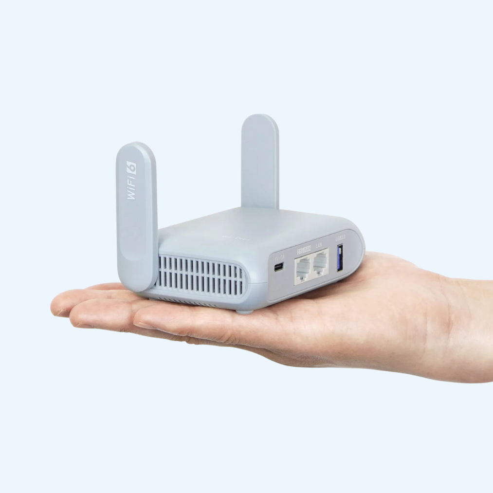 Small gray router held in a hand against a white background